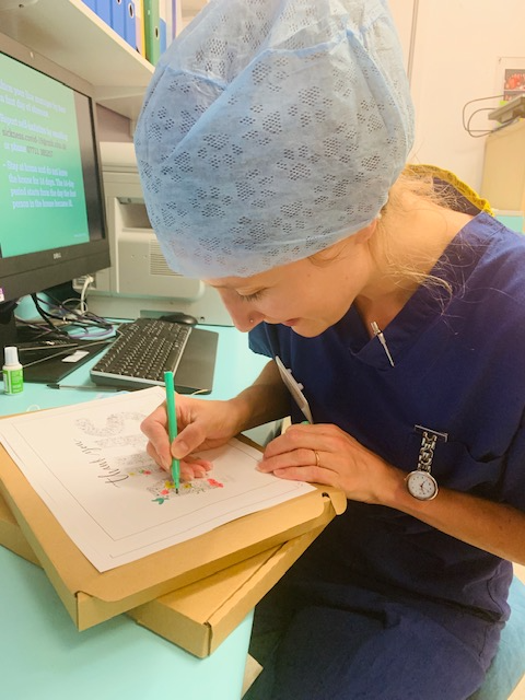 An NHS worker colouring in a drawing made by 'A Space Between' 