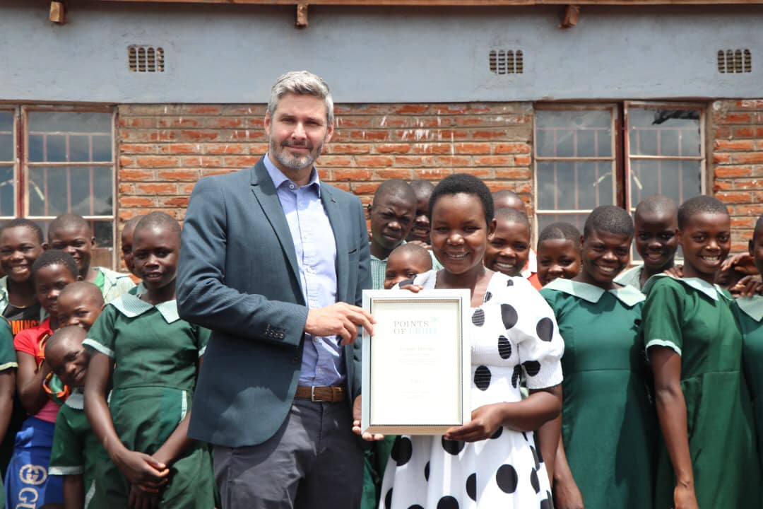 British High Commissioner David Beer presenting Temwani Chilenga with her award on a visit to her school